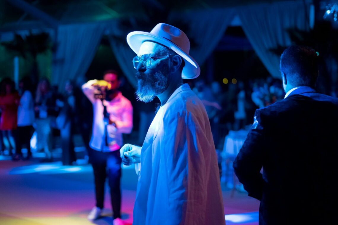 a man in a white hat and sunglasses standing in front of a group of people