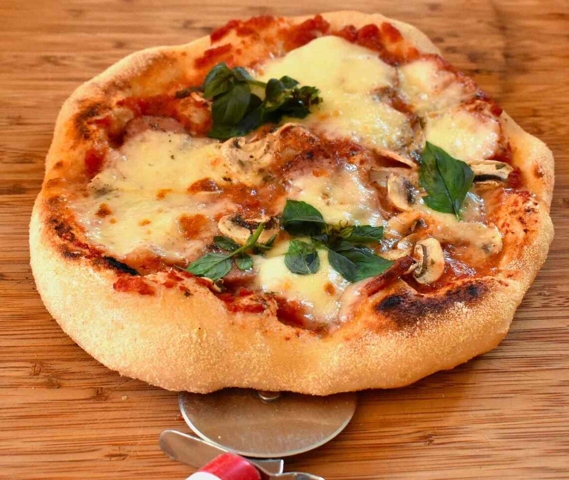 Pizza au fromage, basilic, champignons sur planche, coupe-pizza à côté