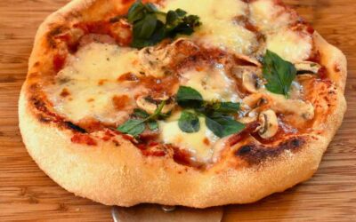Pizza au fromage, basilic, champignons sur planche, coupe-pizza à côté