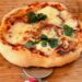 Pizza au fromage, basilic, champignons sur planche, coupe-pizza à côté