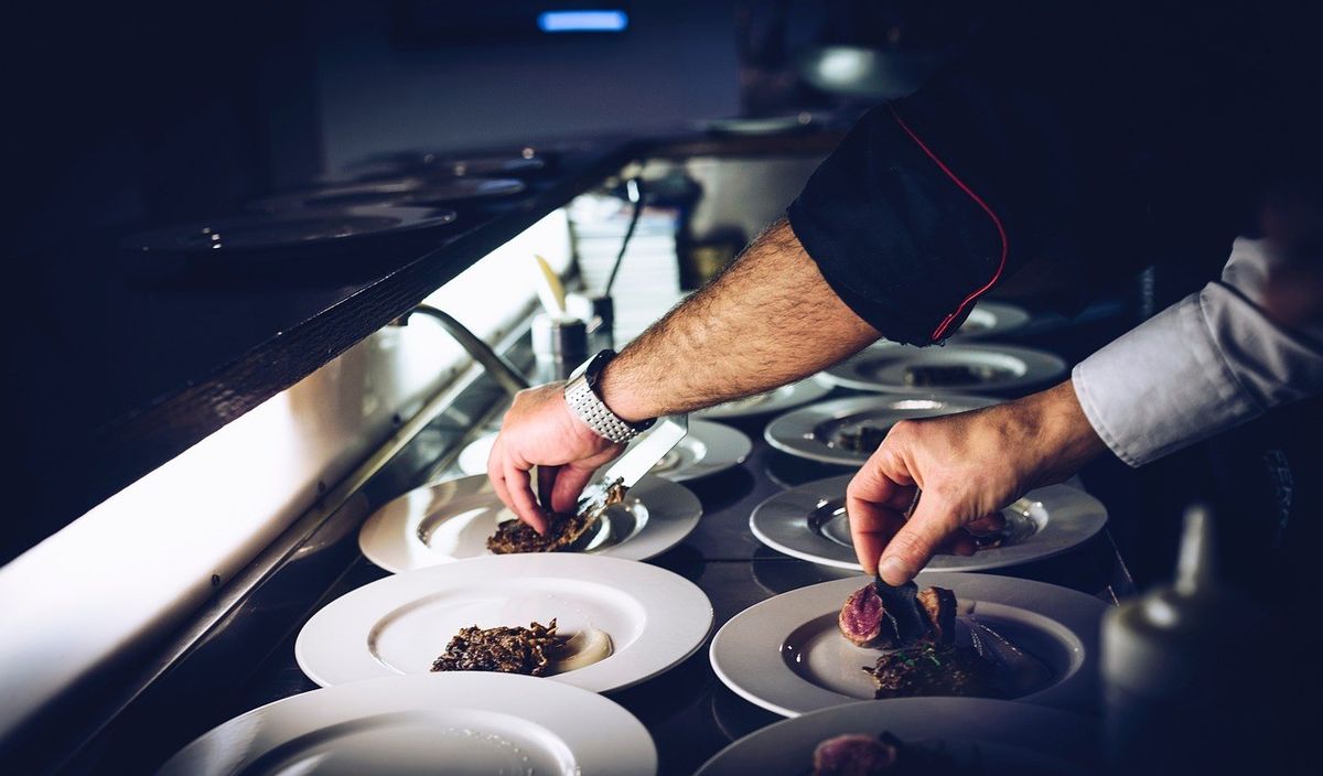 Chef assaisonnant des plats sur une table dans une cuisine professionnelle