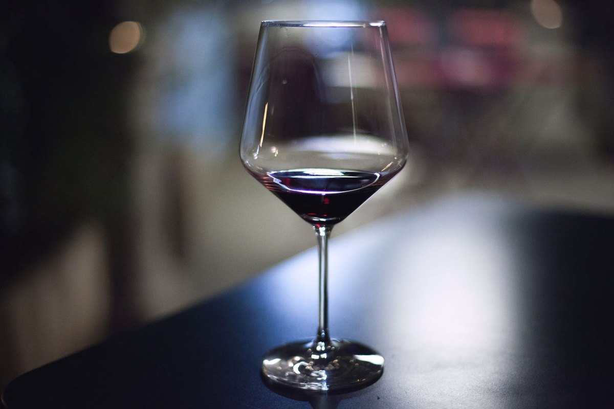 Verre de vin rouge sur table, fond lumineux flou Verre de vin rouge sur table, fond lumineux flou